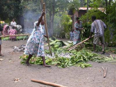 Adding hot stones to cook the laplap